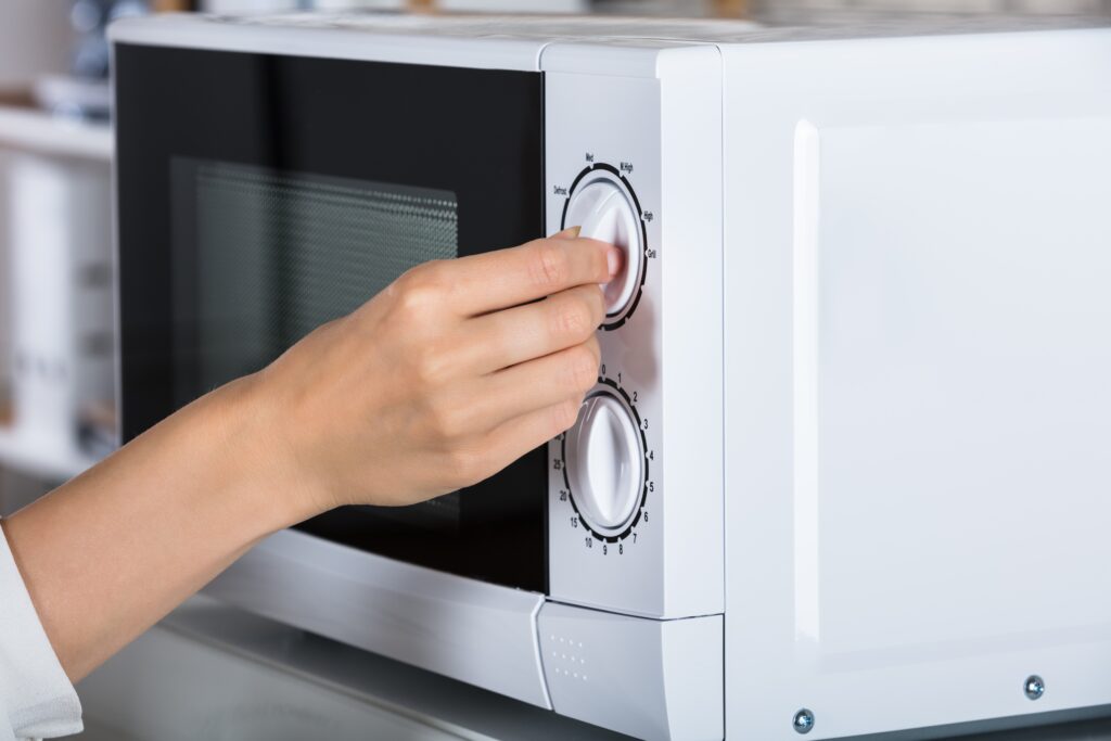 Cropped image of a woman's hand using the microwave - single item that a man-and-van can deliver
